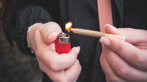 Midsection of person igniting marijuana joint