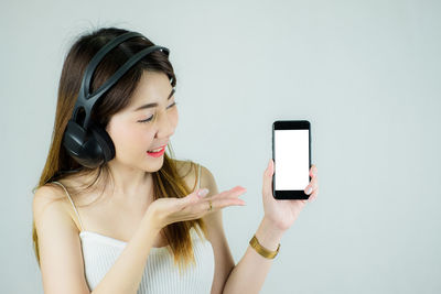 Portrait of young woman using smart phone against white background