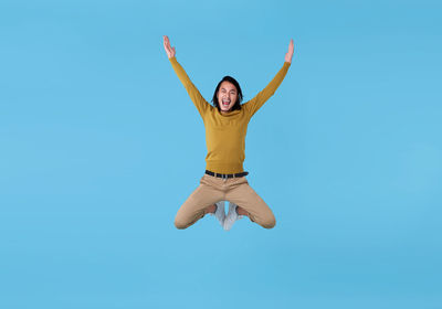 Portrait of woman jumping against blue sky