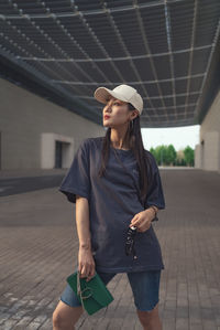 Woman wearing in cap standing on footpath