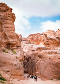 People walking amidst cliff against sky