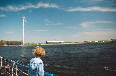 Side view of woman looking at view while standing by railing against sea