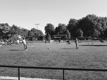 People playing soccer on field against sky