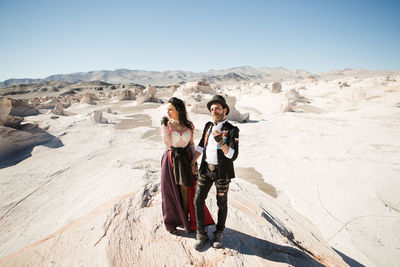 Full length portrait of woman standing on land against sky