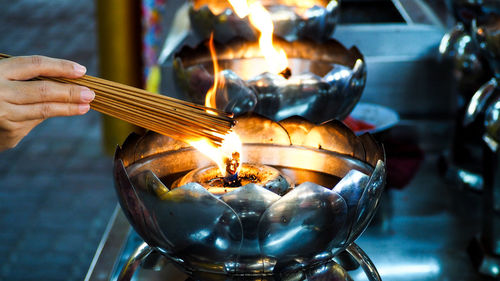 Close-up of hand holding burning incenses
