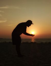 Silhouette man standing on beach during sunset