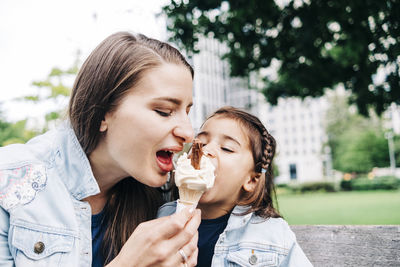 Mother and daughter sharing ice cream at public park