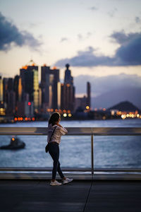 Full length of man standing on railing in city against sky