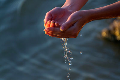 Close-up of hand holding water falling