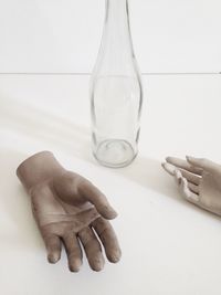 Figurine hands and bottle over white background