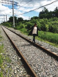 Full length of young woman walking on railroad track