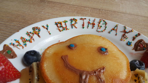 Happy face homemade pancakes with 'happy birthday' decoration. smiley emoji chocolate decoration.