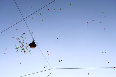 Low angle view of balloons flying against clear blue sky