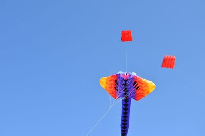 Low angle view of flags against clear blue sky