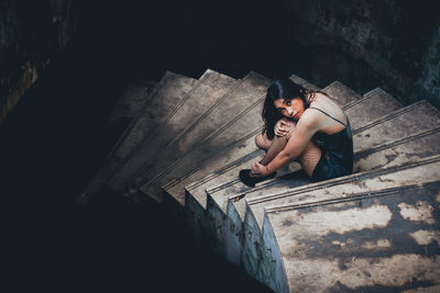 Portrait of young woman sitting on staircase of abandoned house