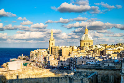 View of buildings in city against cloudy sky