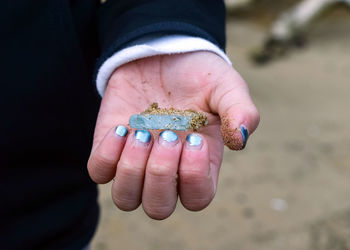 Close-up of hand holding blue stone covered in sand