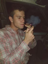 Young man smoking while looking at camera