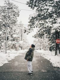 Rear view of woman walking on snow covered road