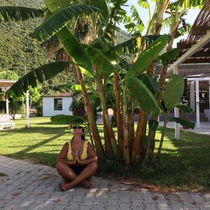 Full length of young woman sitting on grass against trees