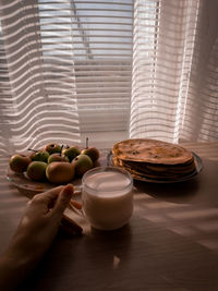 Midsection of person holding ice cream in glass on table