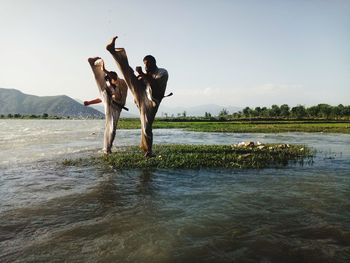 People standing by lake against sky