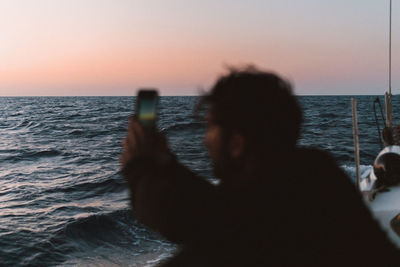 Rear view of people on beach against sky during sunset