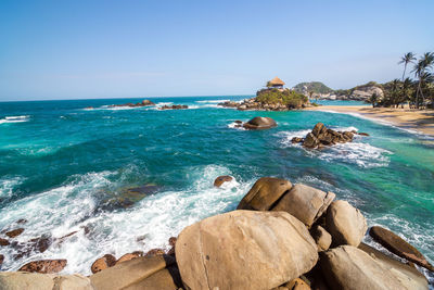 Rock formations in sea against clear sky at tayrona national park