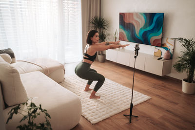 Side view of young woman exercising at home