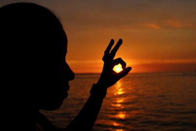 Silhouette woman gesturing against sky during sunset