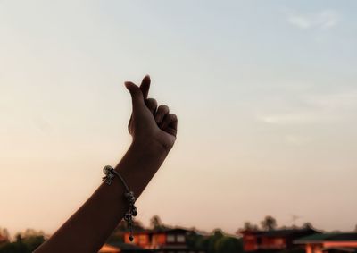 Close-up of person hand against sky during sunset