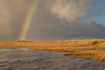 Scenic view of rainbow over sea against sky