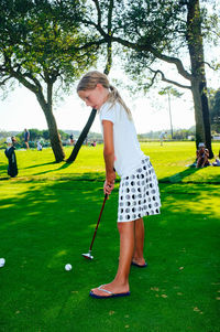 Side view of girl playing golf in park