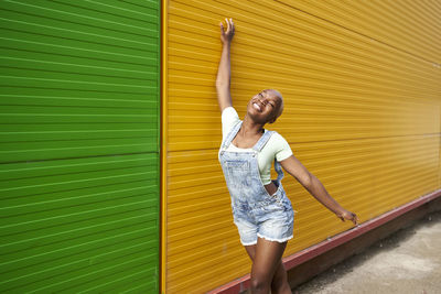 Full length of a young woman standing against yellow wall