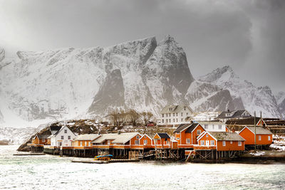 Scenic view of sea by snowcapped mountains against sky