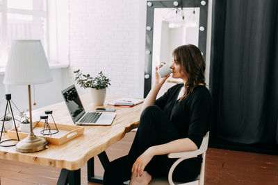 Young woman using phone while sitting on table