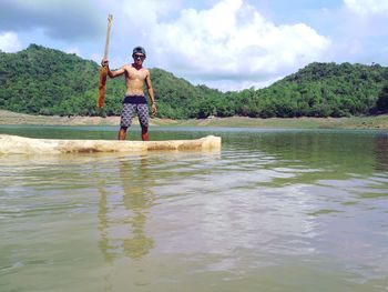 Full length of shirtless man in lake against sky