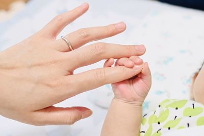 Midsection of mother holding baby hand