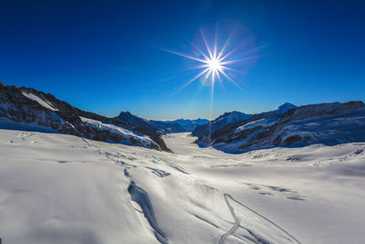 Scenic view of snowcapped mountains against blue sky