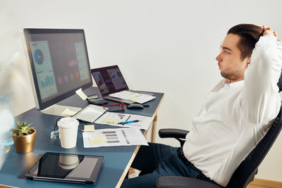 Young businessman feeling tired exhausted after long computer work. man working with data on charts