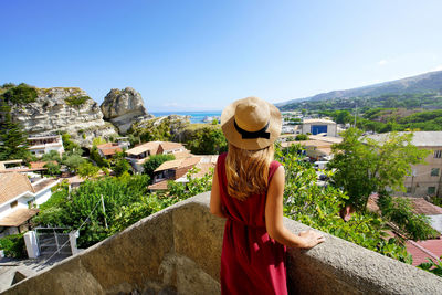 View from behind of beautiful fashion woman in the village of tropea, calabria, italy.