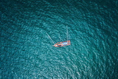 Aerial top view fishing boat sailing on the green sea