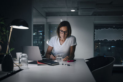 Female professional working late while sitting at desk in office