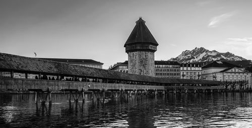 Bridge over river by buildings against sky