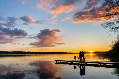 Couple on the pier at a large lake during sunset