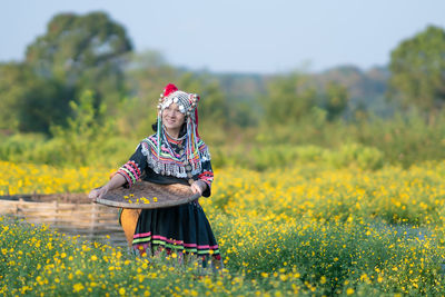 Woman with yellow flowers on field