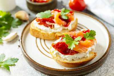 Open sandwiches or bruschetta with salted salmon, cheese and sun dried tomato on a stone table. 