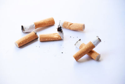 High angle view of cigarette arranged on table against white background