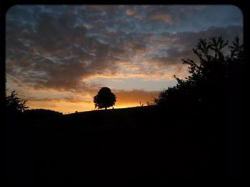 Silhouette of landscape against cloudy sky