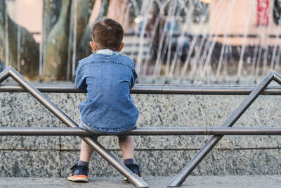 Rear view of boy standing against railing